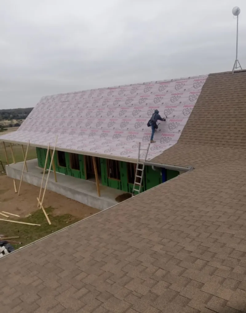 Worker preparing underlayment for a metal roof installation in Mahomet